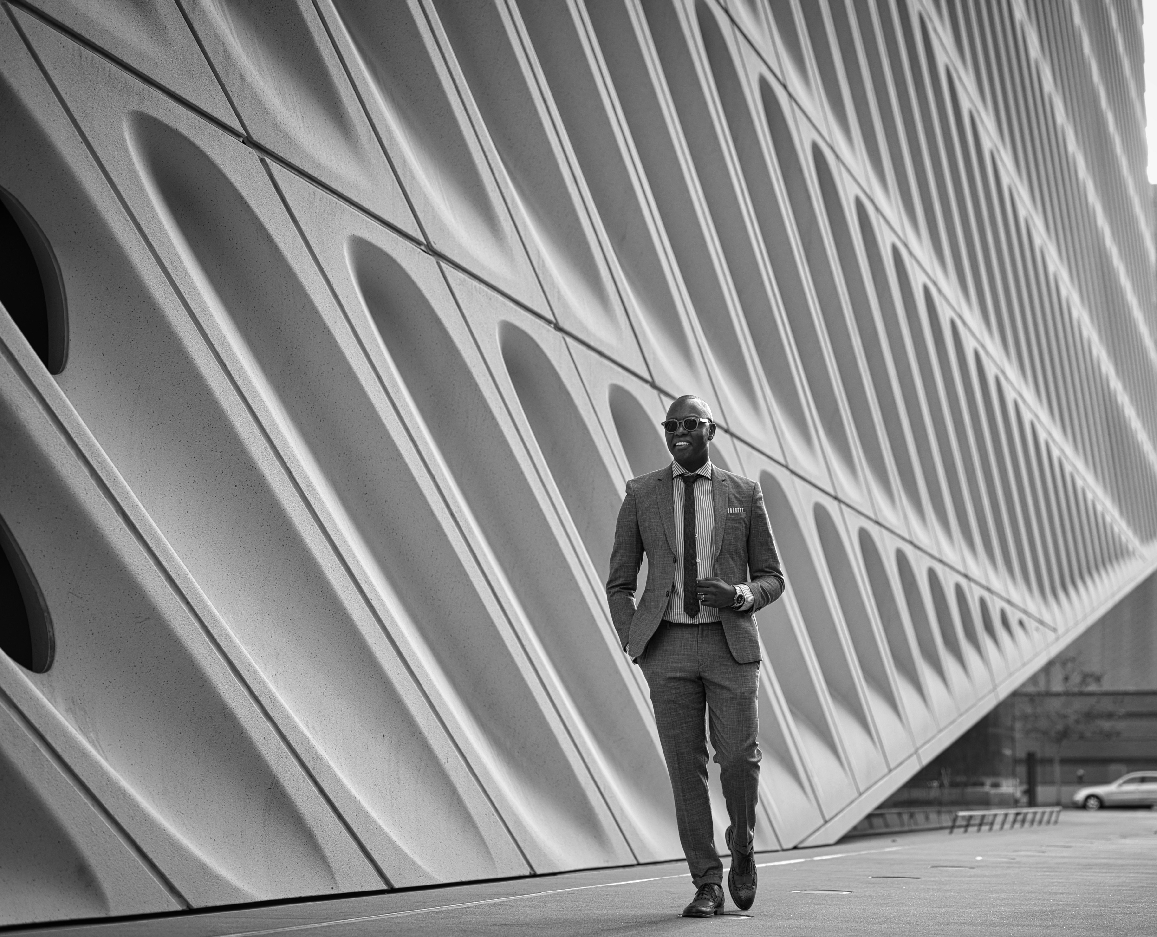 man in black jacket and black pants standing in front of white wall